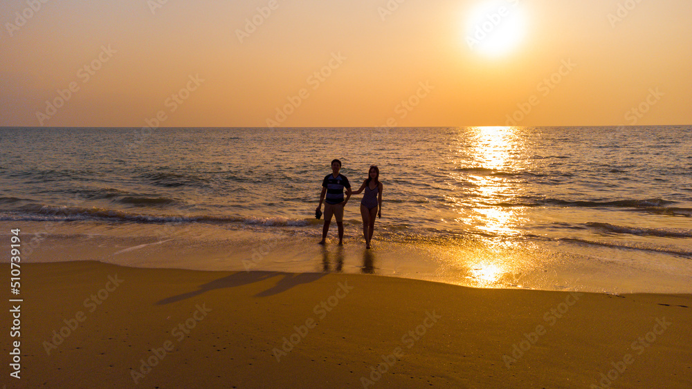 Couple holding hand on the beach with a beautiful sunset in background. man lifting the woman with enjoymoment on view of twilight sunset.