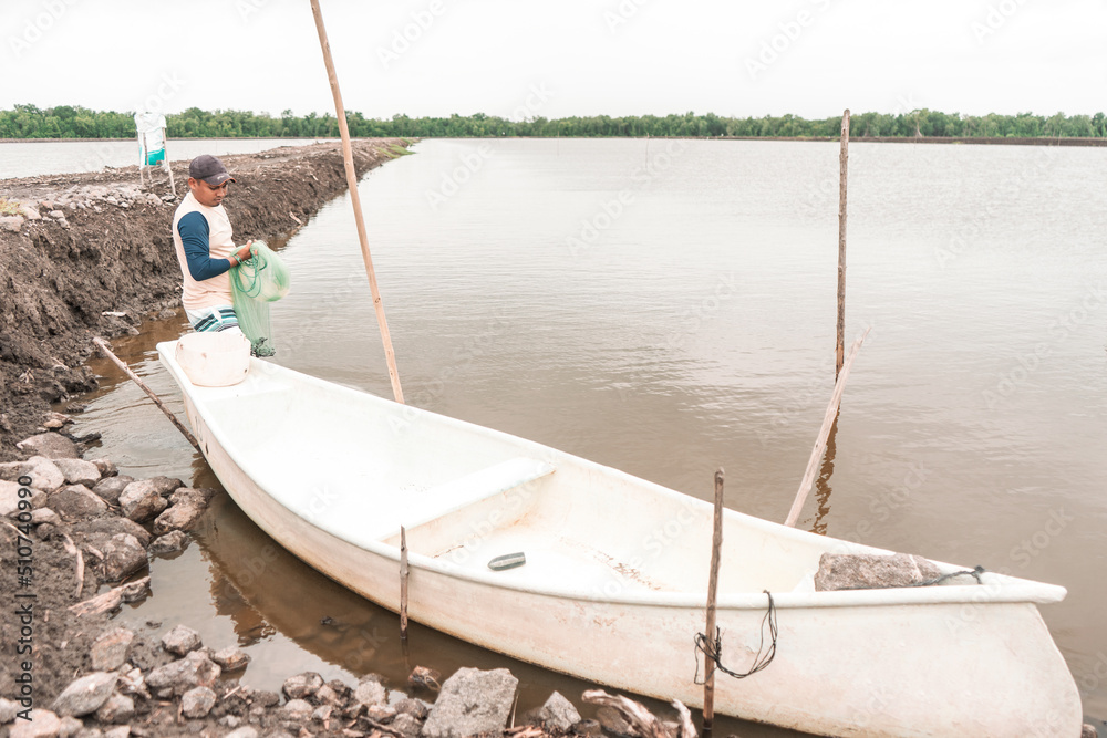Latin man preparing a net in front of a boat to fish for farmed shrimp in Chinandega Nicaragua