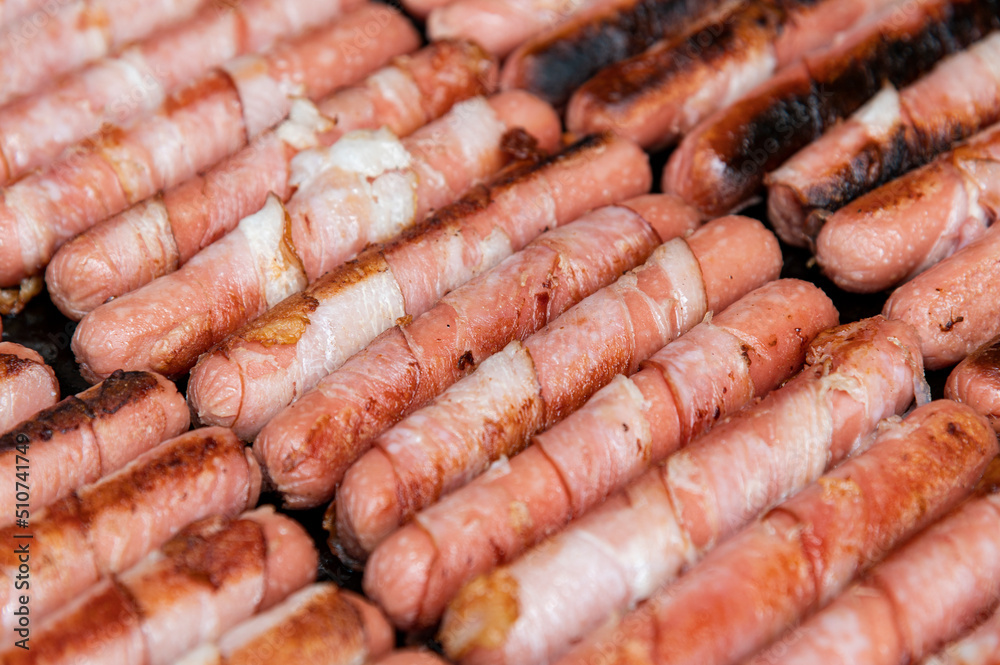 Sausages wrapped with bacon Roasted fat smoked and grilled over a bbq grill on the street food Sausages wrapped with bacon Roasted fat smoked and grilled over a bbq grill on the street food