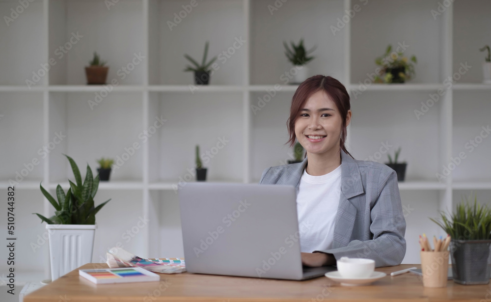 Beautiful smiling young graphic designer sitting at desk in office and working Beautiful smiling young graphic designer sitting at desk in office and working