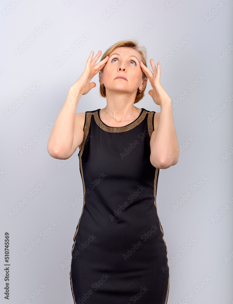 The woman rubs her temples with her fingers and looks up. The woman rubs her temples with her fingers and looks up.