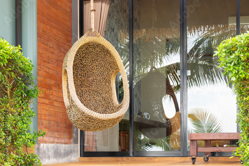 A wicker armchair in the form of a cocoon suspended on the terrace. The recreation scene, the concept of travel and recreation © Евгения Якименко
