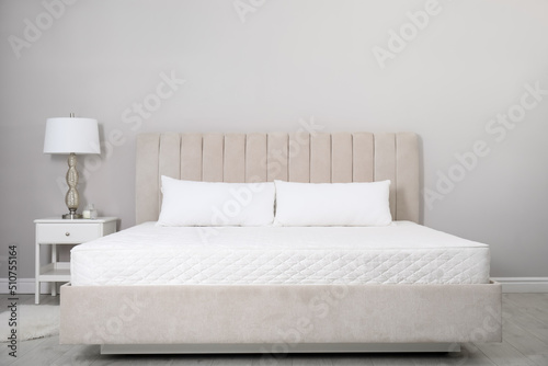 Comfortable bed with soft white mattress and pillows indoors photo