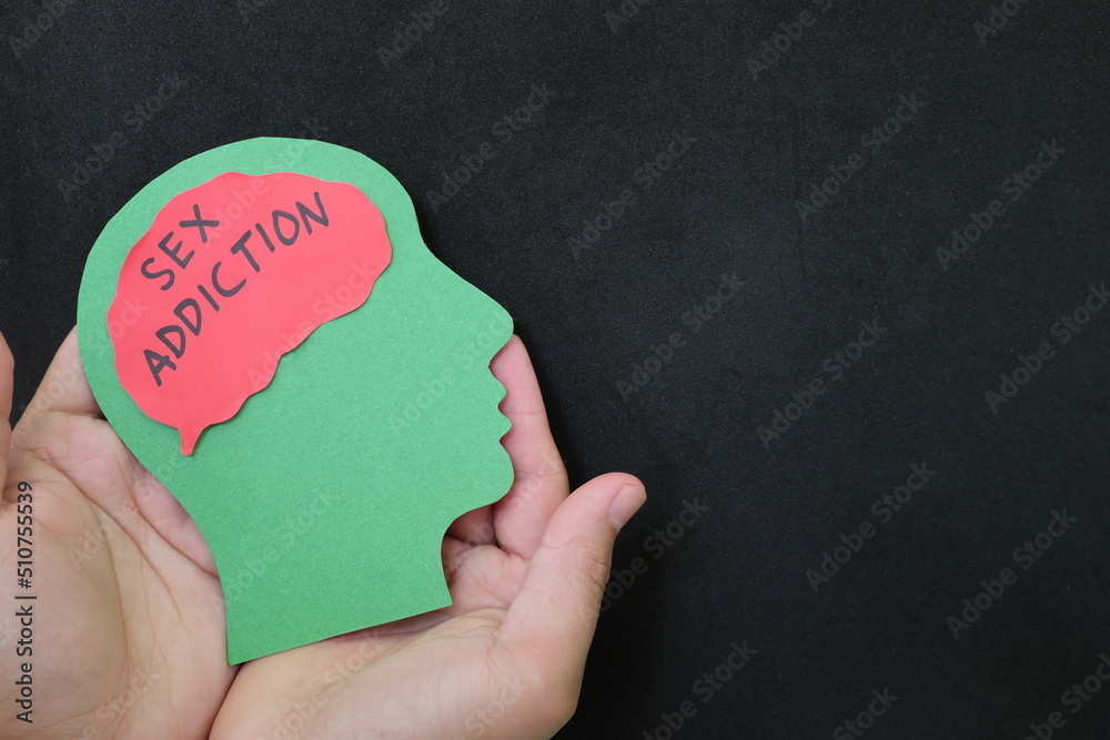 Sex addiction treatment and how to deal with concept. Hand holding human head profile with sex addiction word on brain.