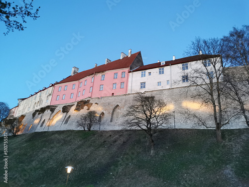 Houses of white and pink color on the medieval defensive wall of the city in the early spring evening against the blue sky. Wanalynn area. photo