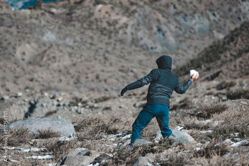 young man from back throwing a snowball on the mountain on a cold winter day