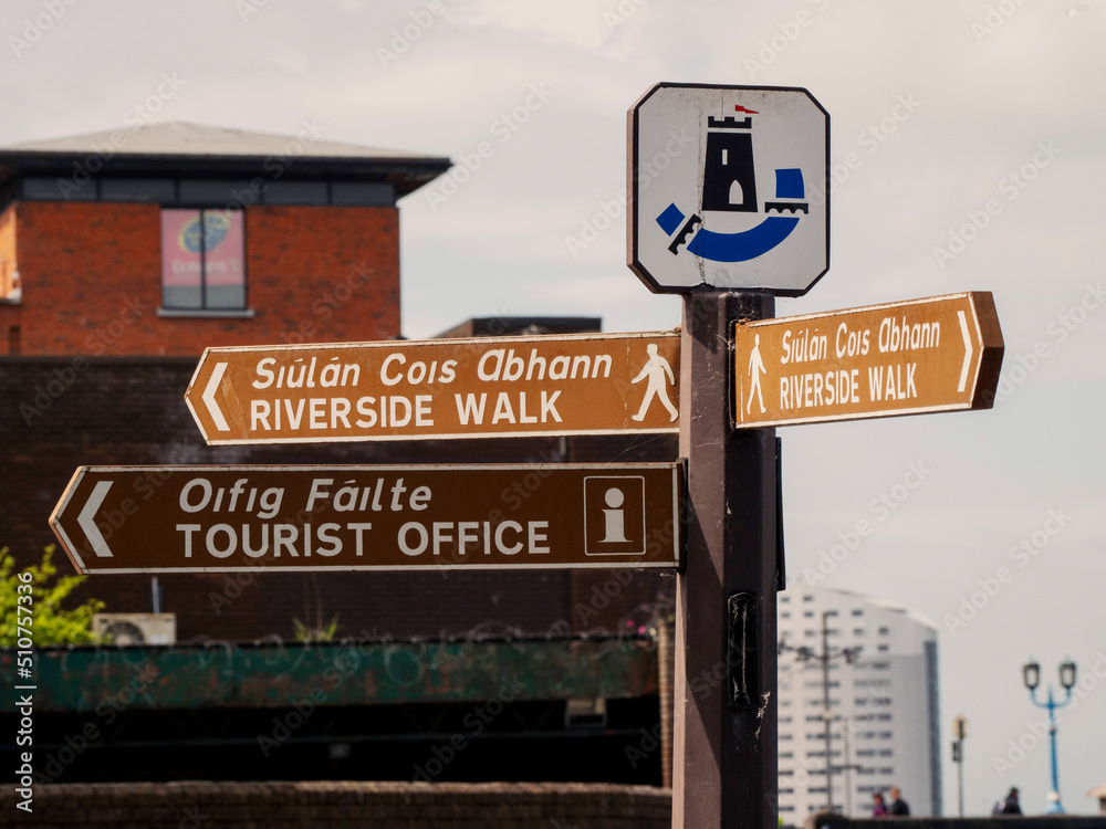 Brown color sign tourist office and riverside walk in English and Irish language in Limerick city, Ireland. Travel and tourism concept