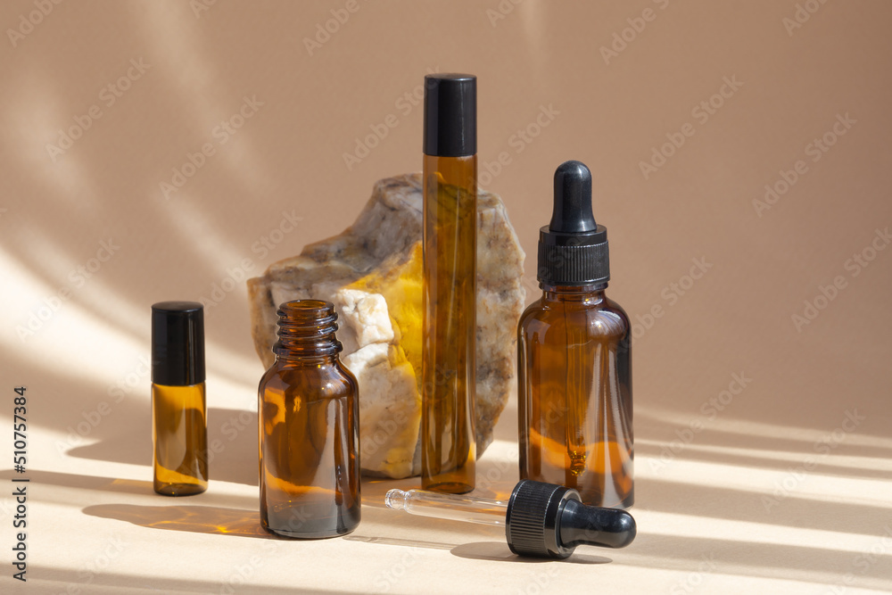 Empty brown amber glass bottles with open and closed dropper lids for cosmetics, oils, serums in sunlight on beige background. Close-up, mockup Empty brown amber glass bottles with open and closed dropper lids for cosmetics, oils, serums in sunlight on beige background. Close-up, mockup