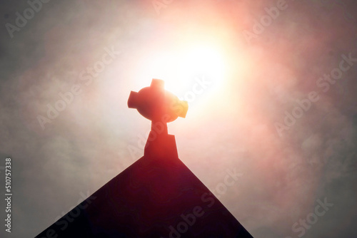 Tableau sur toile Silhouette of a catholic cross on a top of a roof against dark cloudy sky background