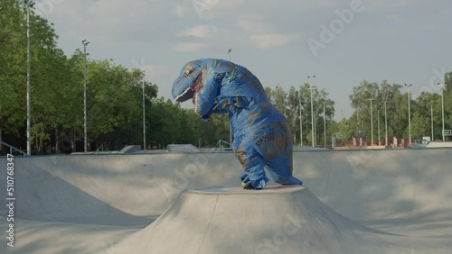 Big blue dinosaur dancing in the urban park at sunrise with no people on the street. Happy everyone. photo