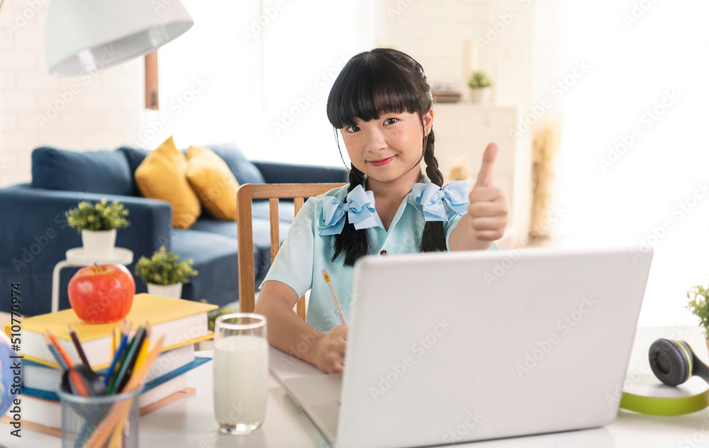 Asian girl using Laptop computer for online study homeschooling during home quarantine. online study, homeschooling, home quarantine, online learning or education technology concept.