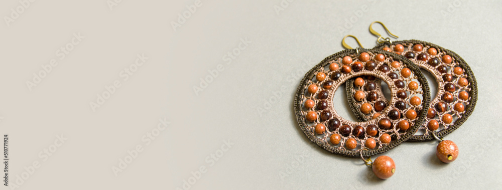 round braided jewelry with natural stones on a gray background. Banner for insertion into site. Place for text cope space. Horizontal image round braided jewelry with natural stones on a gray background. Banner for insertion into site. Place for text cope space. Horizontal image