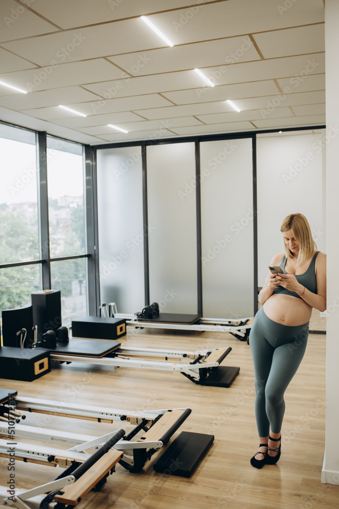 Young pregnant woman practicing yoga at home and using phone Young pregnant woman practicing yoga at home and using phone