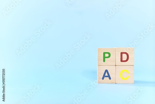 PDCA or Plan Do Check Act cycle method concept. Wooden blocks in blue background with copy space. 