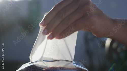 Closeup view 4k stock video footage of white paper tissue in metal container box standing on table outdoors in street sunny restaurant. Female hand takes one paper napking blowing by wind photo