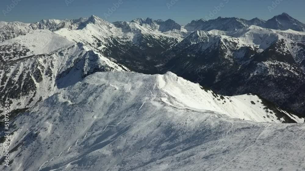 Crisp winter mountain aerial with hikers seen on summit ridge below Crisp winter mountain aerial with hikers seen on summit ridge below