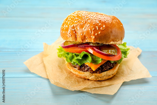 Tasty burger on light blue wooden table. Fast food