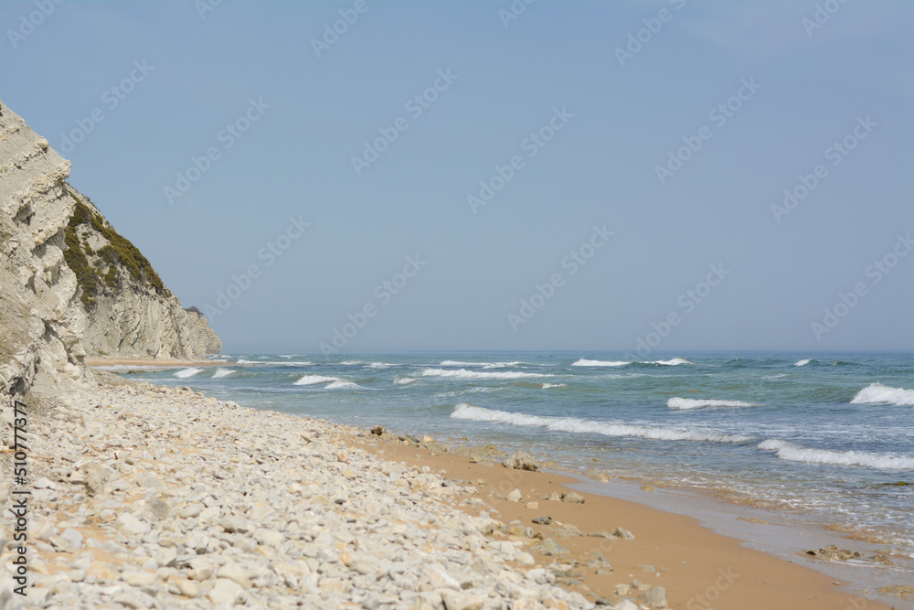Beautiful view of sandy beach with rocks and sea. Summer vacation