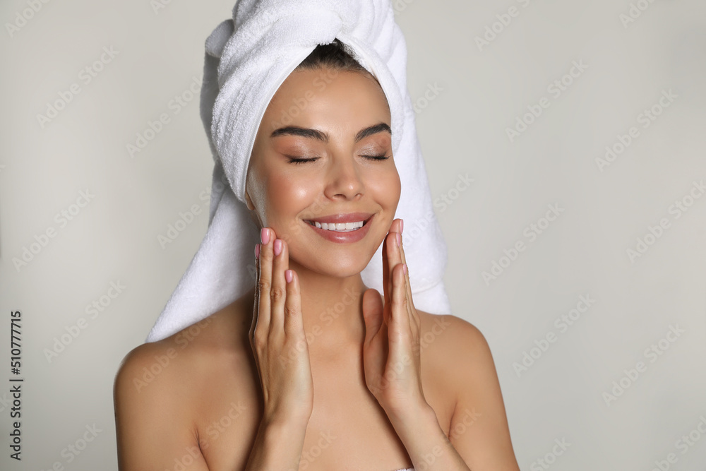 Beautiful young woman with towel on head against light background Beautiful young woman with towel on head against light background