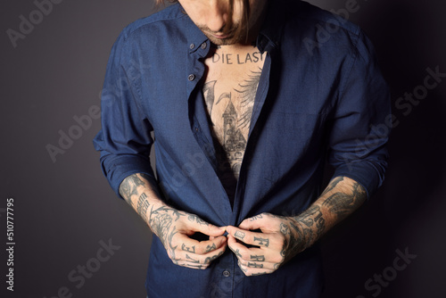 Young man with tattoos on body against black background, closeup