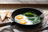 Delicious fried egg with spinach served on wooden table, closeup