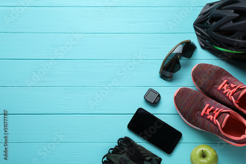 Flat lay composition with different cycling accessories on turquoise wooden background, space for text