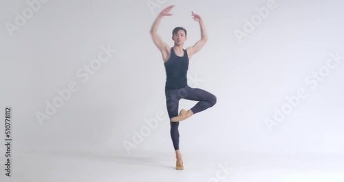 Young male ballet dancer performs pirouette and acrobatic elements in ballet dance, white background.