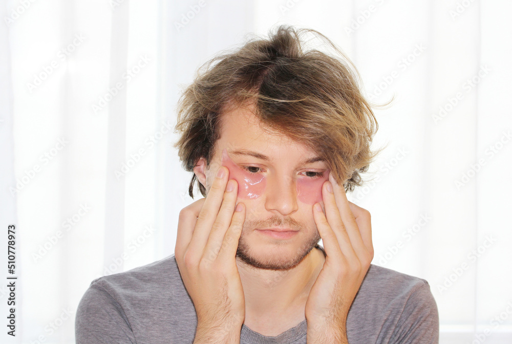 Anti-aging eye therapy. young man taking care of his undereye wrinkles applying facial mask. Dark Circles.Eye patches.. Anti-aging eye therapy. young man taking care of his undereye wrinkles applying facial mask. Dark Circles.Eye patches..