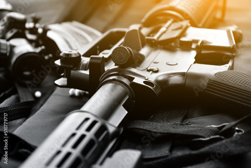 Fototapeta Airsoft gun or BB gun equipments, bullets, gun body, and binocular on dark leather floor background, soft and selective focus