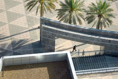 Unidentifiable silhouettes of people crossing a modern square in Dubai, UAE.