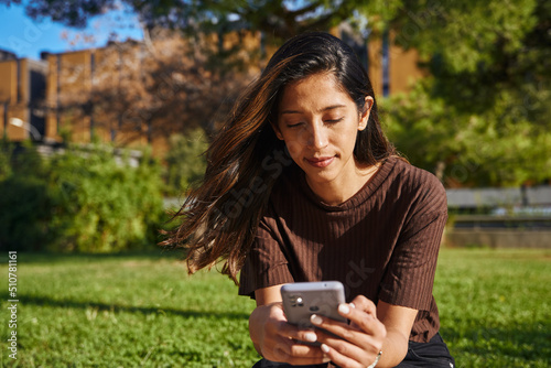 Businesswoman sitting and text messaging in park