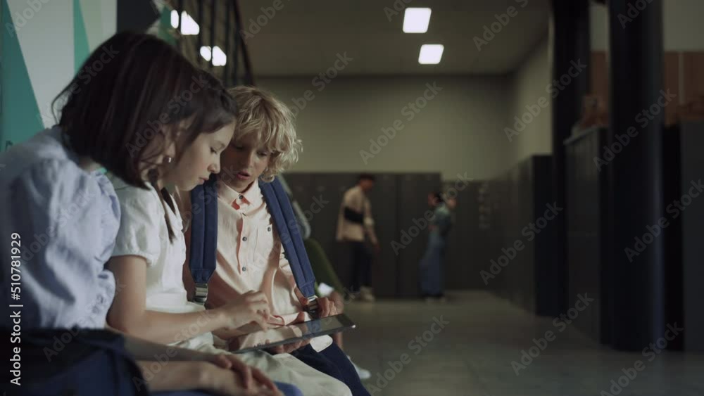 Three focused students sitting with tablet in school hall. Preteen communication Three focused students sitting with tablet in school hall. Preteen communication