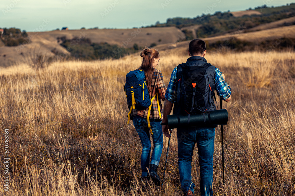 Couple with backpacks hiking together in nature on autumn day. Couple with backpacks hiking together in nature on autumn day.