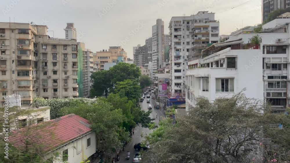 Street Road Between Old Buildings With Passing Cars And Motorcycles In Mumbai City, India. - High-Angle Shot Street Road Between Old Buildings With Passing Cars And Motorcycles In Mumbai City, India. - High-Angle Shot
