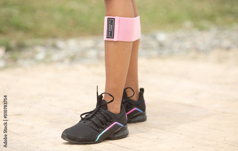 Girl's legs with a resistance band made of fabric.