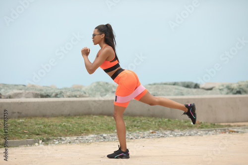 Portrait of a charming black fit girl in sportswear doing training in the background of the sea.