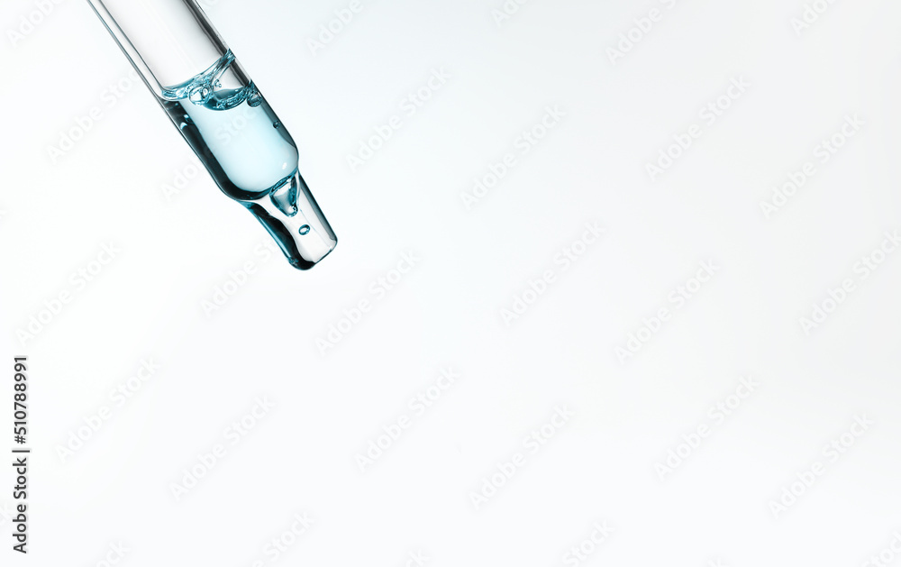 Closeup of pipette with serum, hyaluronic acid on blue background. Cosmetics and healthcare concept. Dose of essential oill, retinol with air bubbles. Beauty product presentation, front view, macro