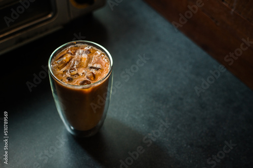 Ice coffee on a table with cream being poured into it showing the texture and refreshing look of the drink