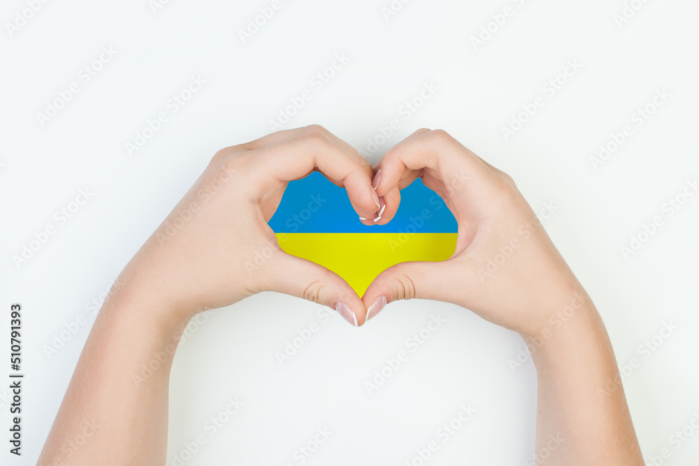 Fototapeta premium Heart with flag of Ukraine in female hands on white background