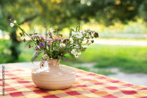 Bouquet of summer flowers in ceramic vase on table on terrace. Fresh Field flowers in vase, closeup. Cozy home decor of patio yard. Still life. Women day or wedding concept. festive background 