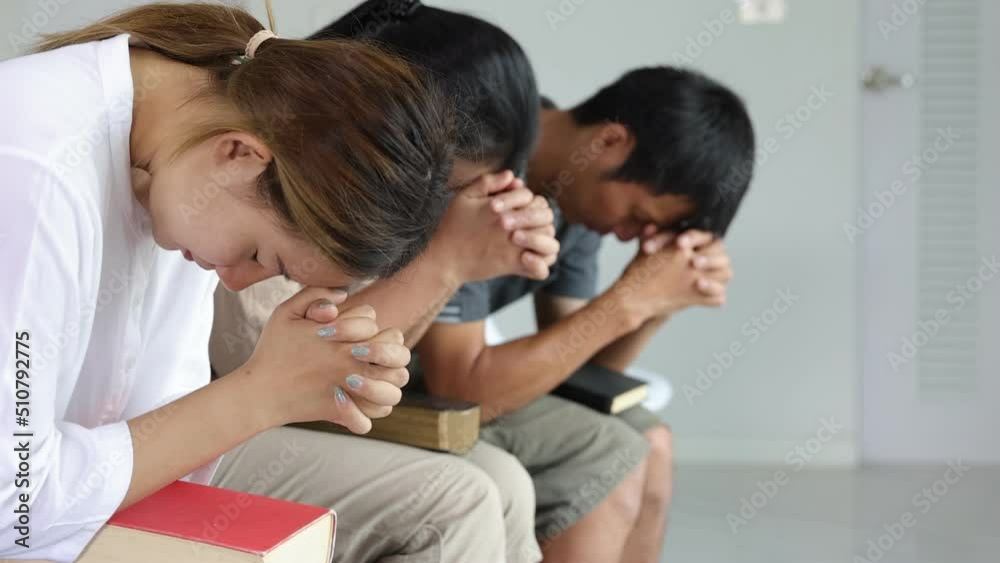 Young woman praying among other religious people indoors. Religious beliefs Christian life crisis prayer to god. Young woman praying among other religious people indoors. Religious beliefs Christian life crisis prayer to god.