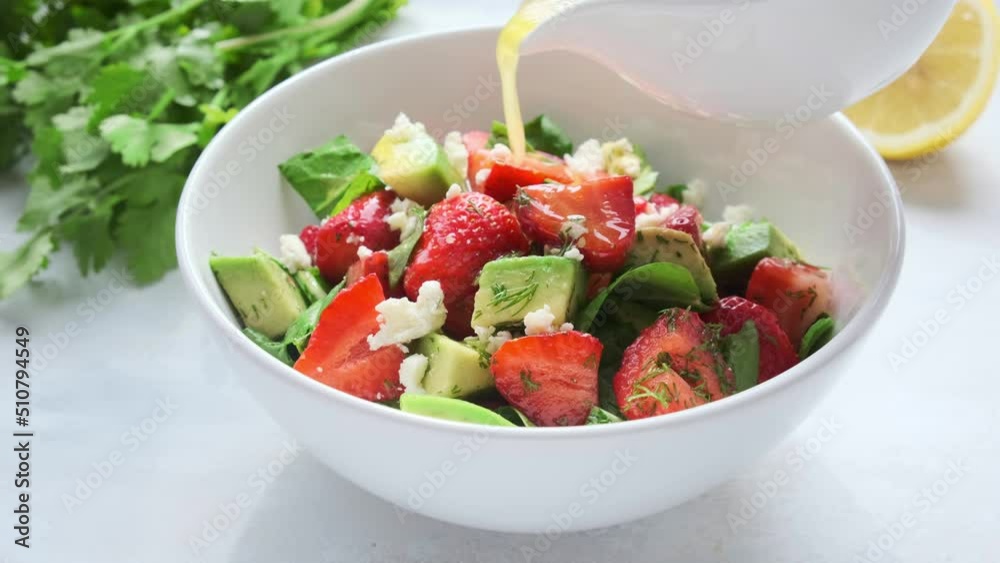Strawberry, avocado and feta cheese salad with mustard dressing in white bowl. Summer recipe. Strawberry, avocado and feta cheese salad with mustard dressing in white bowl. Summer recipe.