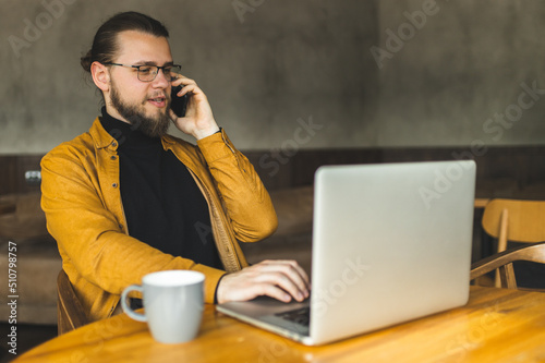 The guy programmer works in a cafe. The guy works remotely in a cafe. Distance learning. Programmer. Hipster.