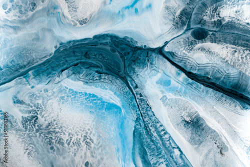 Liquid art texture with pouring colors. Fluid backdrop with flows and cells, waves. Abstract background with splatter inks. Blue colors mixes on macrophotography picture.