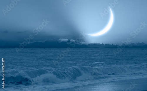 Ramadan Concept - Crescent moon over the sunset clouds with powerful sea wave