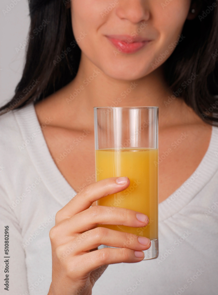 Young woman holding an orange juice glass. Young woman holding an orange juice glass.