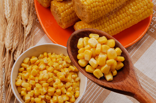 bowl of fresh sweet corn spoon and ears of wheat and corn background