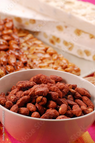 Caramelized sweet nuts bowl and nougats background.