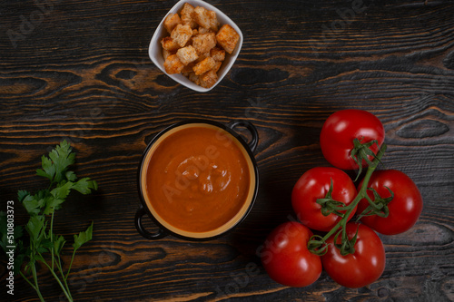 Tomato soup on wooden table, top view