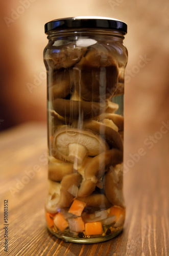 A jar of beautiful pickled mushrooms on a wooden table photo